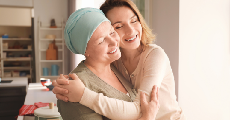 Two women, one who is wearing a head scarf, hug each other and smile