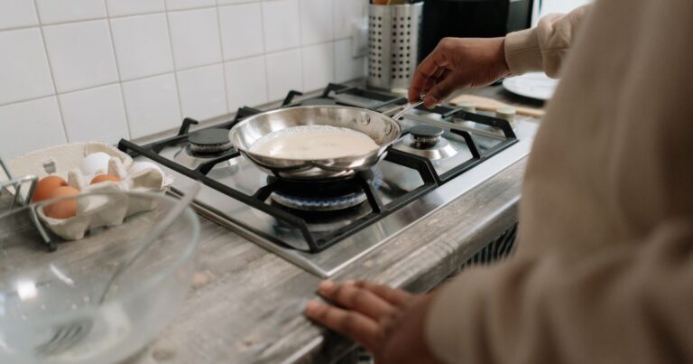 A person cooks eggs in a stainless steel frying pan. Stainless steel is an example of a safer alternative to cookware containing PFAS.